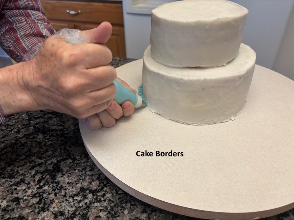Cake with base icing. Hand position for border placement shown